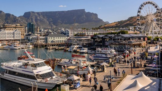 Yachts in harbour at waterfront with ferris wheel and mountain backdrop